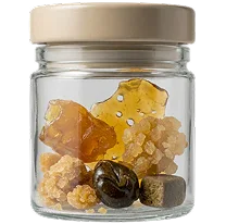 Glass jar holding amber cannabis concentrates, shatter pieces, and hash balls